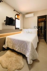本图贡萨尔维斯Malbec Casa Hotel的卧室配有白色的床,墙上配有电视