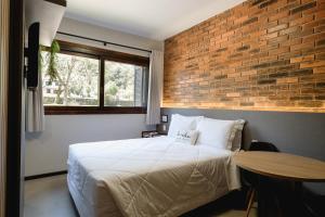 本图贡萨尔维斯Malbec Casa Hotel的一间卧室设有一张床和砖墙