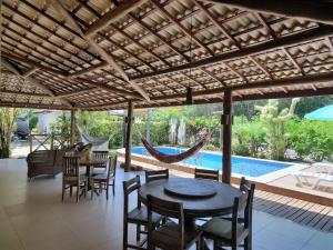 马塔迪圣若昂Linda casa 4/4 com piscina na Praia do Forte.的天井配有桌椅和吊床。