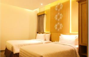 雅加达UNUMA HOTEL的酒店客房,配有两张带白色床单的床