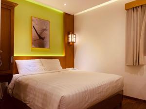雅加达UNUMA HOTEL的卧室配有白色床和黄色墙