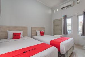 井里汶RedDoorz Plus Syariah @ Tuparev Cirebon 3的两张位于酒店客房的床铺,配有红色枕头
