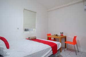 Kalibanteng-lorRedDoorz Hostel near Lawang Sewu Semarang的卧室配有1张床、1张桌子和1把椅子