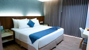 Mojokerto莫佐克托阿优拉日出酒店的卧室配有一张大白色的蓝色床单