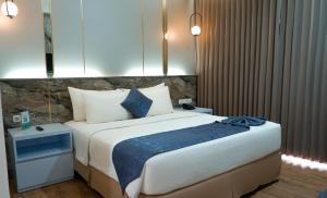 Mojokerto莫佐克托阿优拉日出酒店的一间卧室配有一张带蓝白色枕头的大床