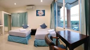 甲米镇Marina Seaview Krabi的酒店客房设有两张床、一张桌子和一张桌子。