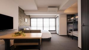 大阪MIMARU Osaka Shinsaibashi North的一间酒店客房,配有一张床铺、一张桌子和一台电视