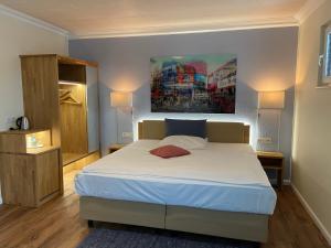 布茨巴赫Hotel Hessischer Hof的卧室配有一张床,墙上挂有绘画作品