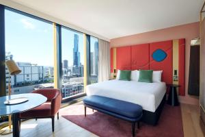 墨尔本Quincy Hotel Melbourne的酒店客房带一张大床、一张桌子和椅子。
