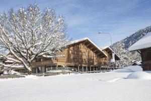 格施塔德Gstaaderhof - Active & Relax Hotel的雪中一座大木结构建筑,有树