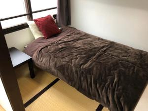 小樽小樽市炫酷公寓的卧室里的一张床铺,上面有红色枕头