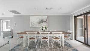 萨拉曼德湾Seaside Sanctuary - Waterfront Luxury Home with Heated Pool的白色的用餐室配有桌椅