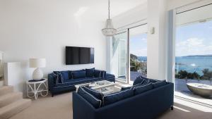 尼尔森湾Riviera - Panoramic Water Views In The Heart Of Nelson Bay的客厅配有蓝色的家具和大窗户