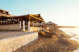 毕达哥利翁Potokaki Beachfront Hotel的海滩上的一组椅子和遮阳伞