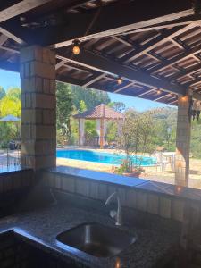 卡洛斯-巴尔博萨Sítio dos Coqueiros, em meio a natureza com piscina的一个带水槽和游泳池的厨房