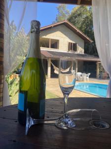 卡洛斯-巴尔博萨Sítio dos Coqueiros, em meio a natureza com piscina的一张桌子上坐着一瓶葡萄酒和一杯