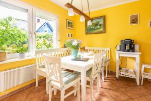 欧巴德伍斯图Ferienhaus Ankerherz的用餐室设有黄色的墙壁和白色的桌椅