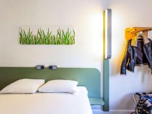 安特卫普宜必思经济型酒店安特卫普中央车站店的卧室配有一张带绿色床头板和墙上草的床铺。