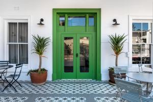 开普敦iGadi House Boutique Hotel的白色房子的绿色门,有植物