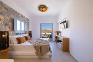 阿斯提帕莱亚镇Infinity Blue Suites & Spa的一间卧室配有一张床、一张书桌和一个窗户。