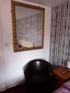 TarlandAberdeen Arms Hotel Tarland的一面墙面上的镜子,一面靠着一把黑椅子