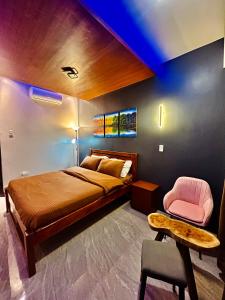 邦劳Sky Traveller Suites的一间卧室配有一张床和一张粉红色的椅子