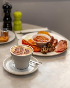 考文垂Ramada Hotel & Suites by Wyndham Coventry的餐桌,茶几,咖啡和一盘食物