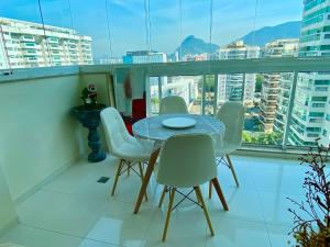 里约热内卢Barra da Tijuca Depto decorado en Exclusivo Resort的阳台的用餐室配有桌椅