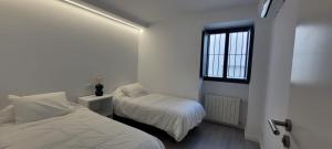 塞维利亚COZY & MODERN APARTMENT HOMBRE DE PIEDRA的一间白色卧室,配有两张床和窗户