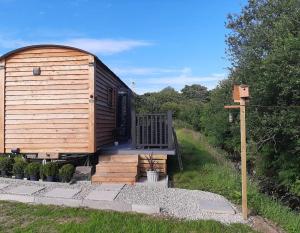 GwalchmaiShepherds Hut with hot tub on Anglesey North Wales的小木屋设有门廊和甲板