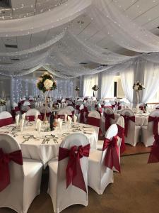 瑟索The Weigh Inn Hotel & Lodges的宴会厅配有白色桌子和红色弓