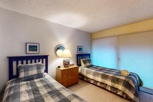 格伦阿伯Gentle Winds 9 10的一间卧室设有两张床和一张桌子上的台灯。