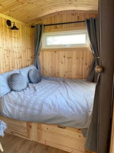 沃里克Beautiful 1 Bed Shepherd Hut in Warwickshire的木制客房的一张床位,设有窗户