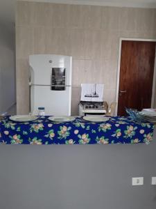 伊塔尼亚恩casa de praia campos的厨房配有冰箱和带盘子的桌子