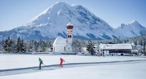 洛伊塔施Landgasthaus Birkegg的两人在教堂前越野滑雪