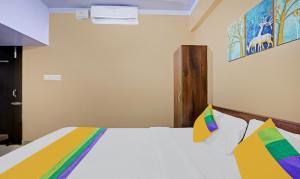 迈索尔Itsy By Treebo - Lotus Inn的卧室配有白色的床和色彩缤纷的枕头