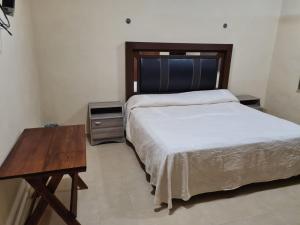 伊萨马尔Hotel La Piramide Izamal的一间卧室配有一张床和一张木桌
