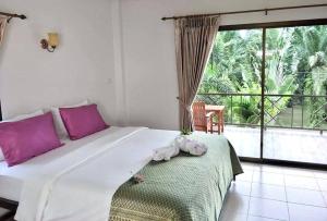 蔻立萨瓦斯蒂家庭住宿及游泳池度假村的一间卧室配有一张带粉色枕头的大床和一个阳台