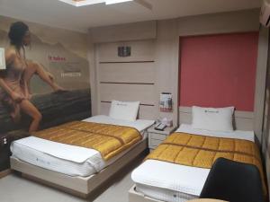 泗川Diamond Motel的一间设有两张床的客房,墙上挂着一张海报