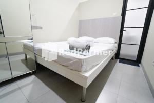 雅加达Tomang Gelong Guest House Syariah Mitra RedDoorz的一张病床,上面有白色的床单和枕头