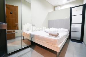 雅加达Tomang Gelong Guest House Syariah Mitra RedDoorz的一间卧室设有一张床和玻璃墙