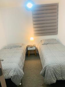 安托法加斯塔SENSACIONAL DEPTO的客房设有两张床和一张带台灯的桌子。