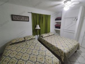 圣卡洛斯Casa Tecalai 5的一间卧室设有两张床和绿帘