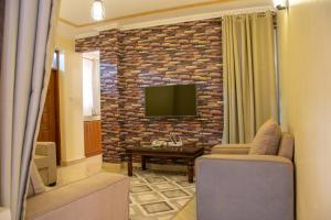 纳库鲁Pearl Suites Apartments的一间客厅,在砖墙上配有电视