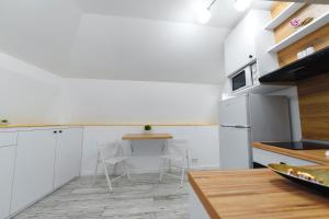 克拉约瓦Bella House的厨房配有白色橱柜和桌椅