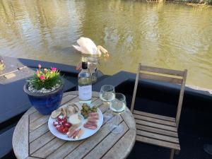 Little BaddowWillow - Cottage on the River, Luxury Houseboat的一张桌子,上面放着一盘食物和一瓶葡萄酒