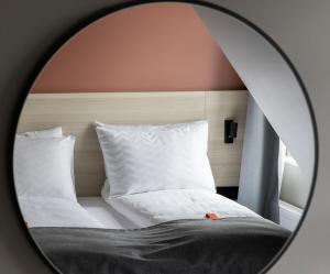 奥斯陆奥斯陆城市之盒酒店的镜子反射着白色床单和枕头的床