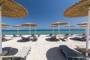 蒂加基Utopia Blu Hotel的海滩上的一组椅子和遮阳伞