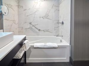 普莱诺Sandman Signature Plano-Frisco Hotel的白色的浴室设有浴缸和水槽。