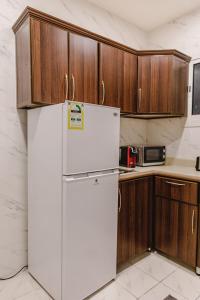吉达Al Butat Al Mummayza的带木制橱柜的厨房内的白色冰箱
